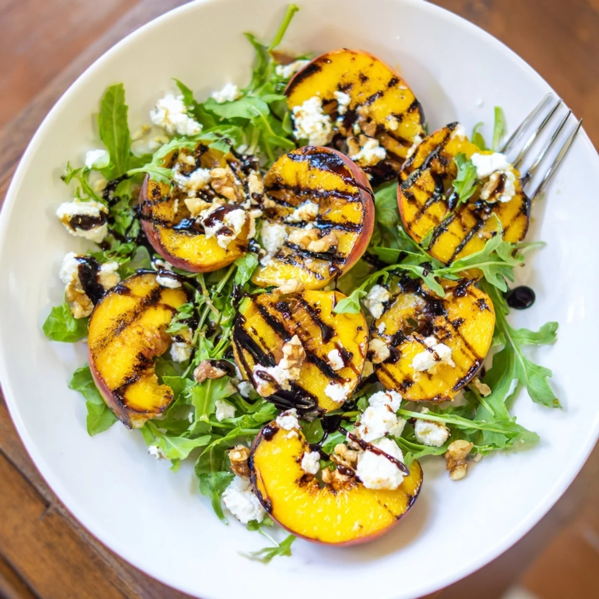 Grilled Peach Salad with Feta and Balsamic Glaze topped with walnuts and greens.