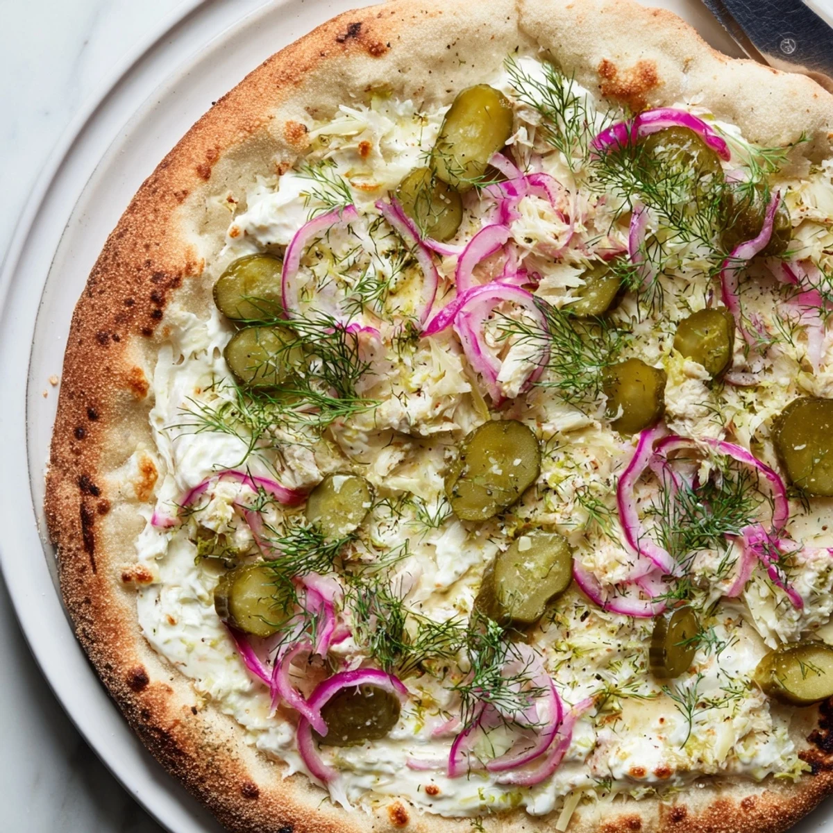 Tangy Pickle Pizza topped with creamy sauce, crunchy pickles, and melted mozzarella.  