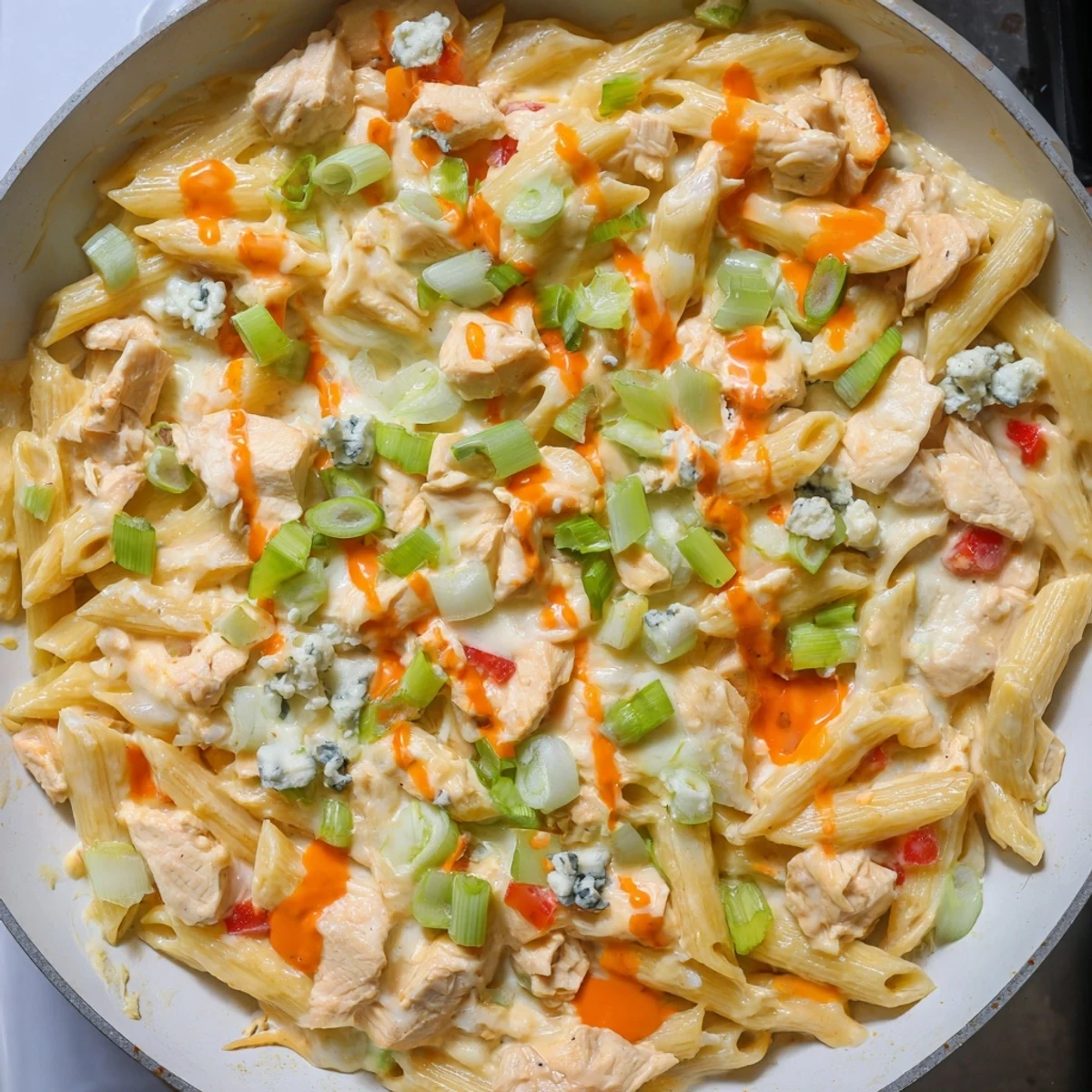 This cheesy, one-pan Buffalo Chicken Pasta skillet showcases tender chicken and vibrant red peppers in a rich sauce.