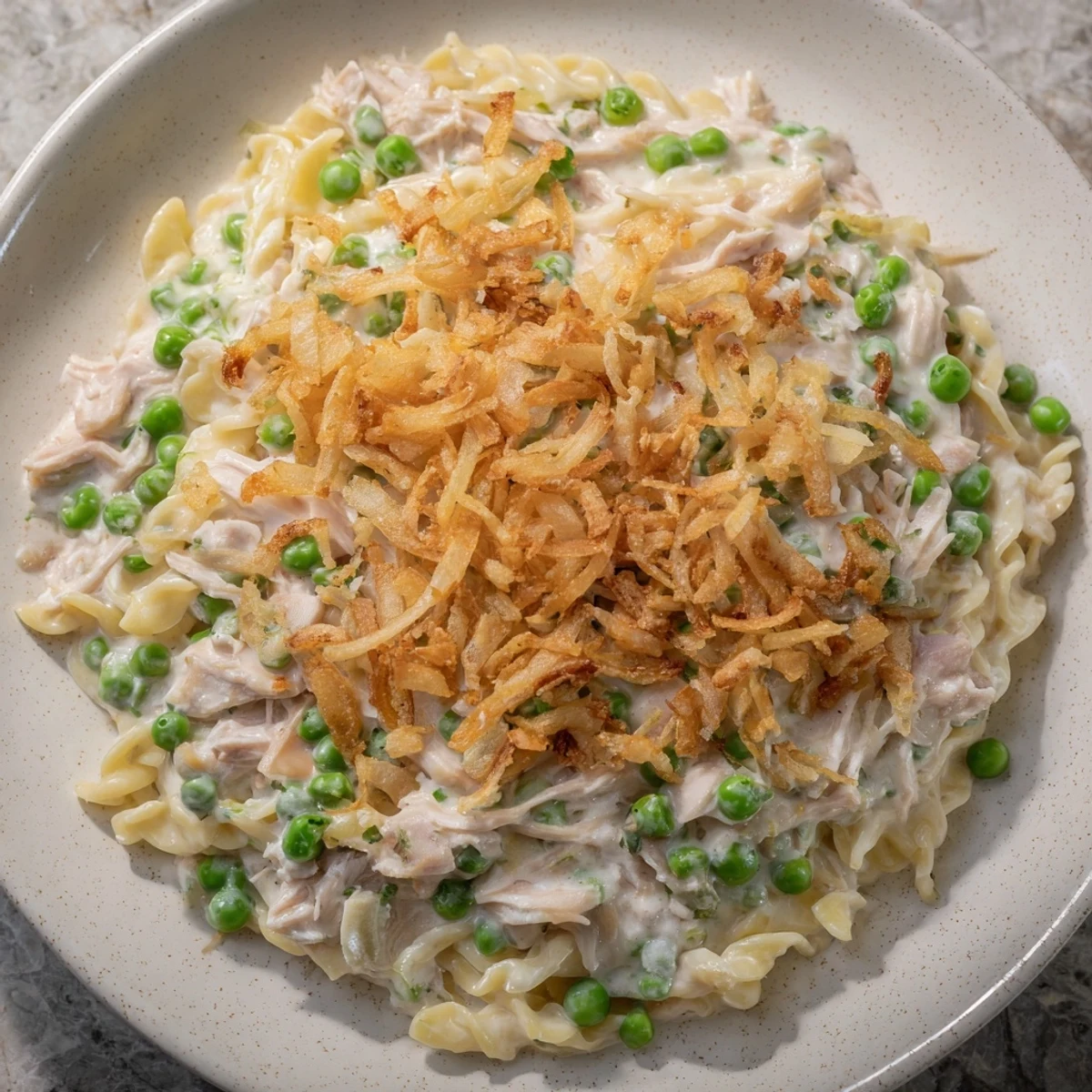 A bubbly, family-style Homemade Tuna Noodle Casserole topped with crunchy fried onions, ready to serve.
