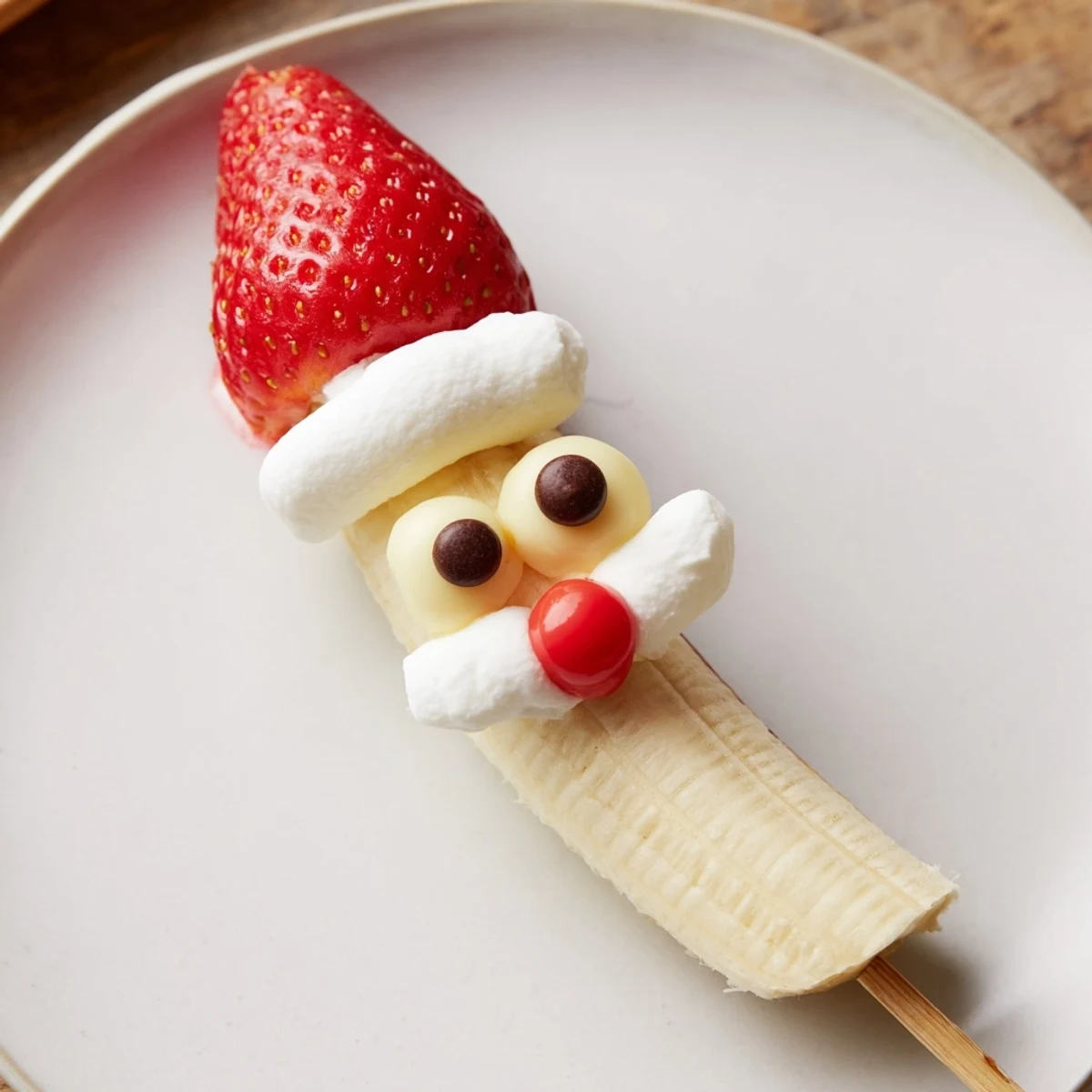 Adorable Banana Strawberry Santa Skewers, a fun, festive snack, show banana slices and strawberry "hats" on skewers.