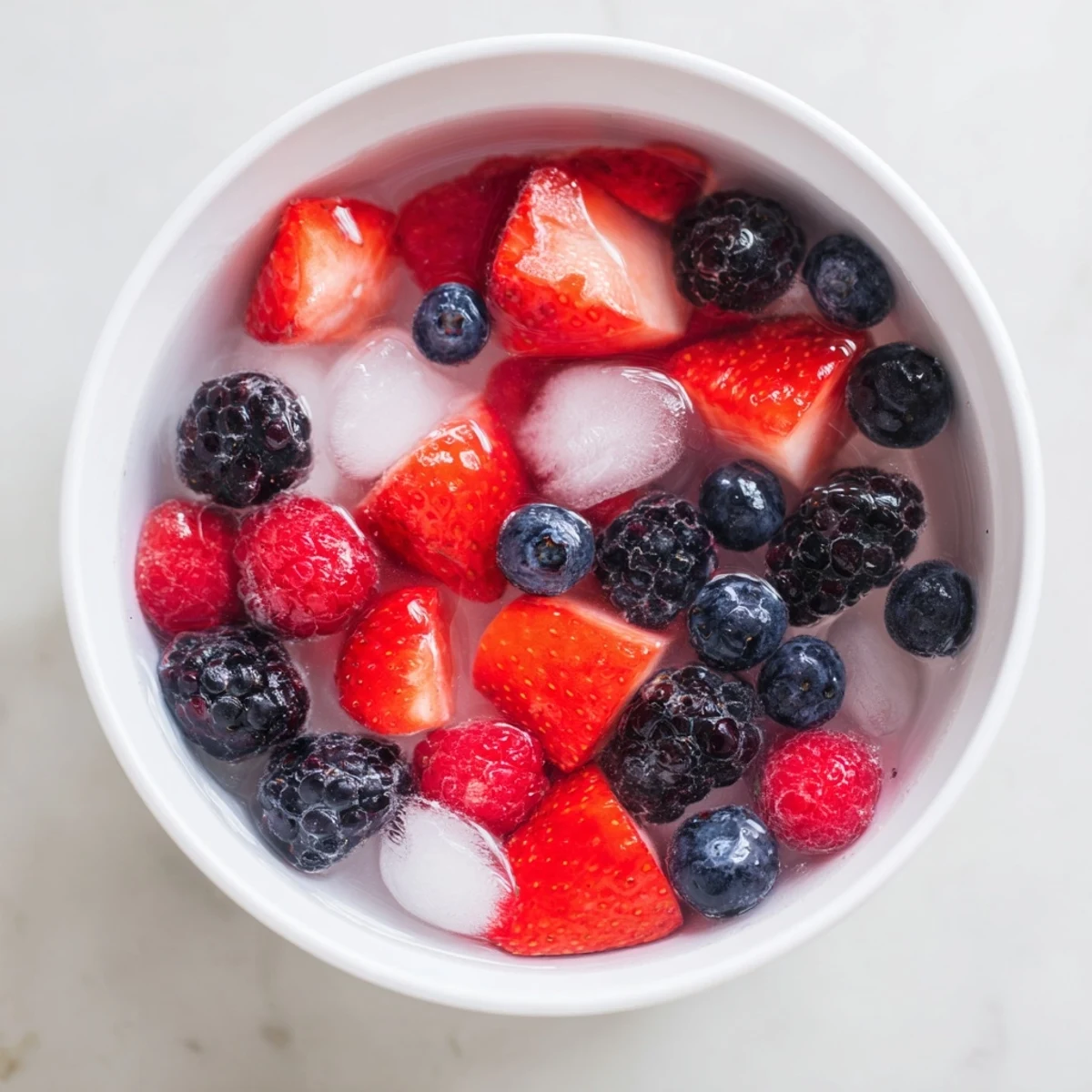 Overhead view of Nature's Cereal Bowl with a medley of antioxidant-rich berries and glistening ice cubes in coconut water.  