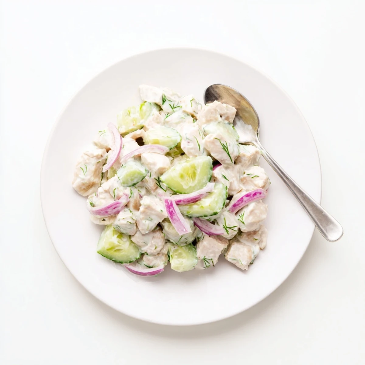 Creamy Cucumber Chicken Salad in a glass serving bowl topped with chopped green onions, a side of crackers, and a linen napkin, perfect for a refreshing high-protein lunch.