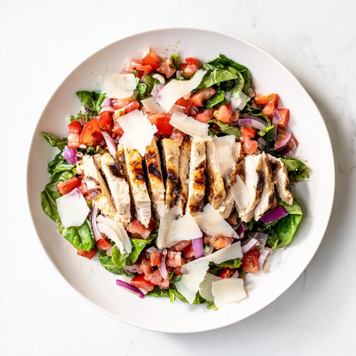 Grilled Bruschetta Chicken Salad on a plate with fresh tomatoes, basil, and mixed greens.  