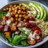 Close-up of a nourishing Buddha Bowl showing fluffy quinoa, caramelized sweet potatoes, and crisp fresh vegetables with avocado slices.