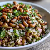 A chilled Southern Black Eyed Pea Salad in a white bowl, featuring celery and mint with a glistening lemon-mint vinaigrette.