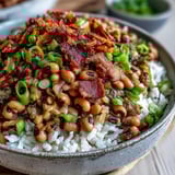 Sizzling bacon renders in a Dutch oven for classic Southern Hoppin' John, filled with aromatics and spices.