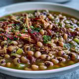 A close-up view of Classic New Years Black-Eyed Peas, featuring tender peas and shredded meat in a rich, savory Creole broth.
