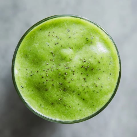 A vibrant glass of Green Detox Smoothie topped with mint leaves, ready to energize your morning.