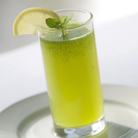 A tall glass of Celery Ginger Lemon Juice filled with vibrant green liquid, topped with ice, fresh celery stalks, and a lemon slice, offering a refreshing morning detox.