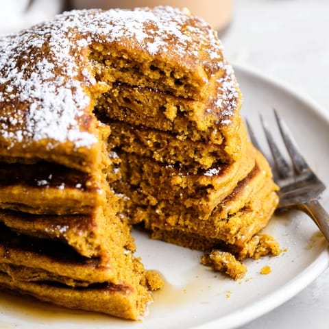 Deliciously warm Gingerbread Pumpkin Muffin Pancakes served with whipped cream and spices.  