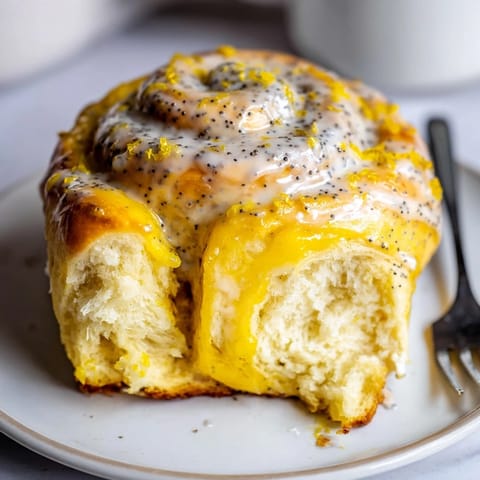 Gooey lemon rolls topped with vibrant icing, perfect for summer brunch gatherings.  