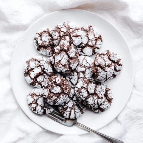 Perfectly round Chocolate Crinkle Cookies with a fudgy interior and beautiful crackled topping, served on a tray.