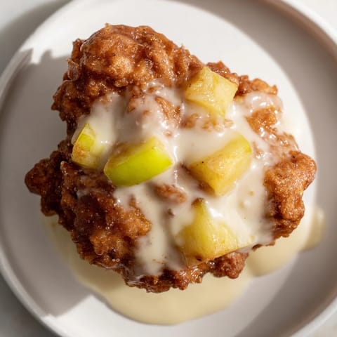 A close-up of a stack of warm apple fritters, showing the tender apple pieces and glistening glaze.