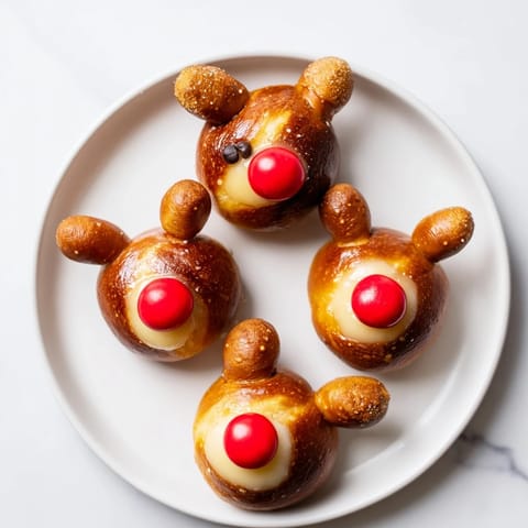 Golden brown Rudolfs Red Nose Pretzel Bites, ready to enjoy, with tiny pretzel antlers and chocolate chip "eyes."