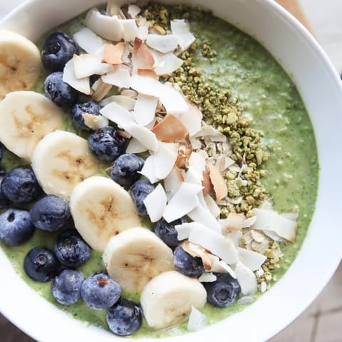 A close-up of vibrant Matcha Overnight Oats with sliced bananas and a sprinkle of coconut.