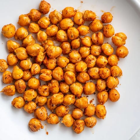 Enjoy a bowl of savory crispy chickpea snack, with visible spices clinging to each crunchy chickpea.