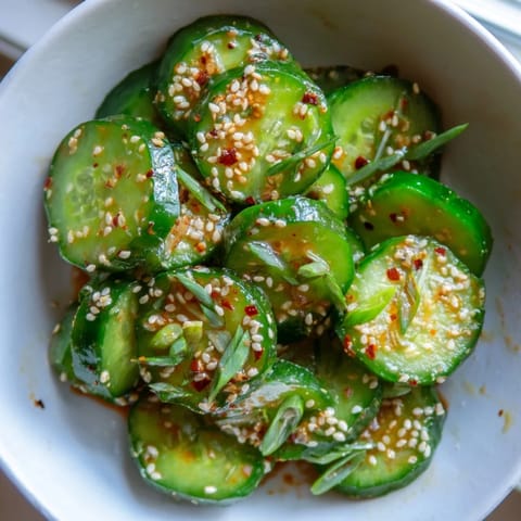 Shake Shake Garlic Cucumbers tossed with minced garlic and chili flakes, served as a crunchy appetizer on a white plate.
