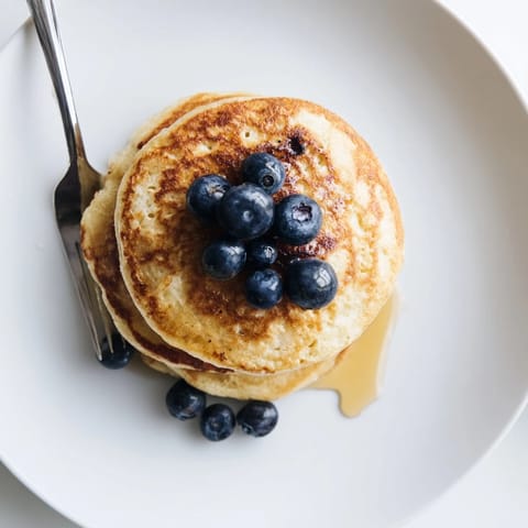 Golden cottage cheese pancakes sizzling on a skillet, served warm with a dollop of Greek yogurt.  