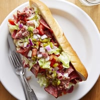 A close-up of a loaded chopped Italian grinder sandwich, with diced salami and provolone nestled in a crisp toasted hoagie roll.